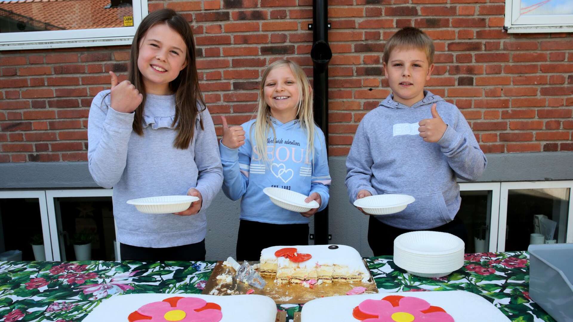 Clara Johansson, Thea Lööf och Enar Axelsson firar rekordförsäljning av majblommor med specialgjord majblomme-tårta på Råda skola.