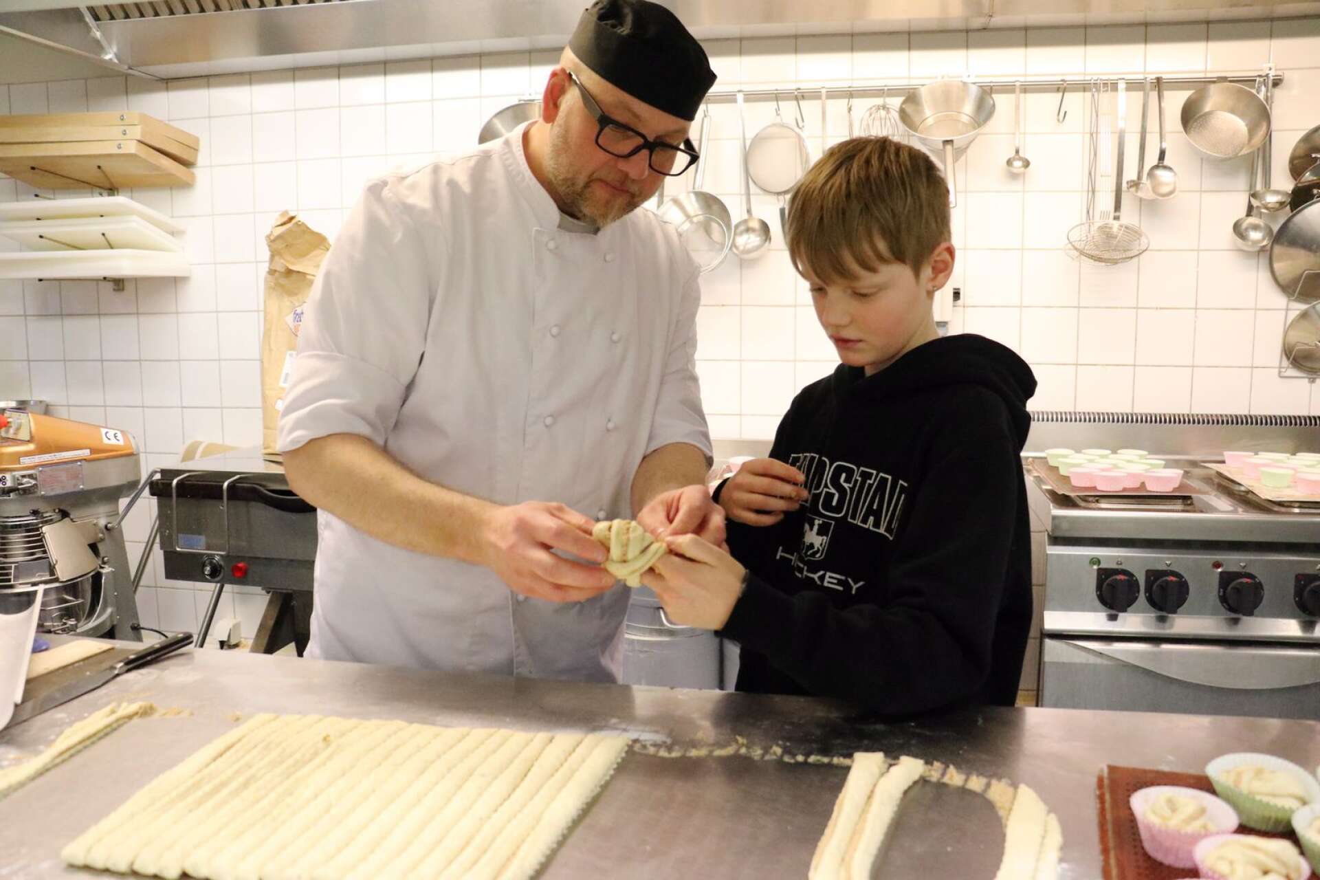 Restaurangläraren Fredrik Bosander visar Finn Hoebe, som går i fjärde klass på Åsenskolan, hur man rullar ihop bullarna.