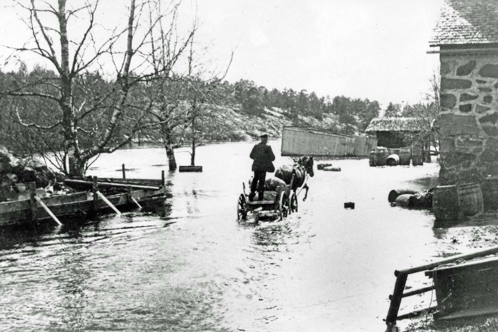 Detta är en klassisk bild från vårfloden 1904. Ett ekipage med häst och vagn passerar genom vattnet som når upp till Stenmagasinet.