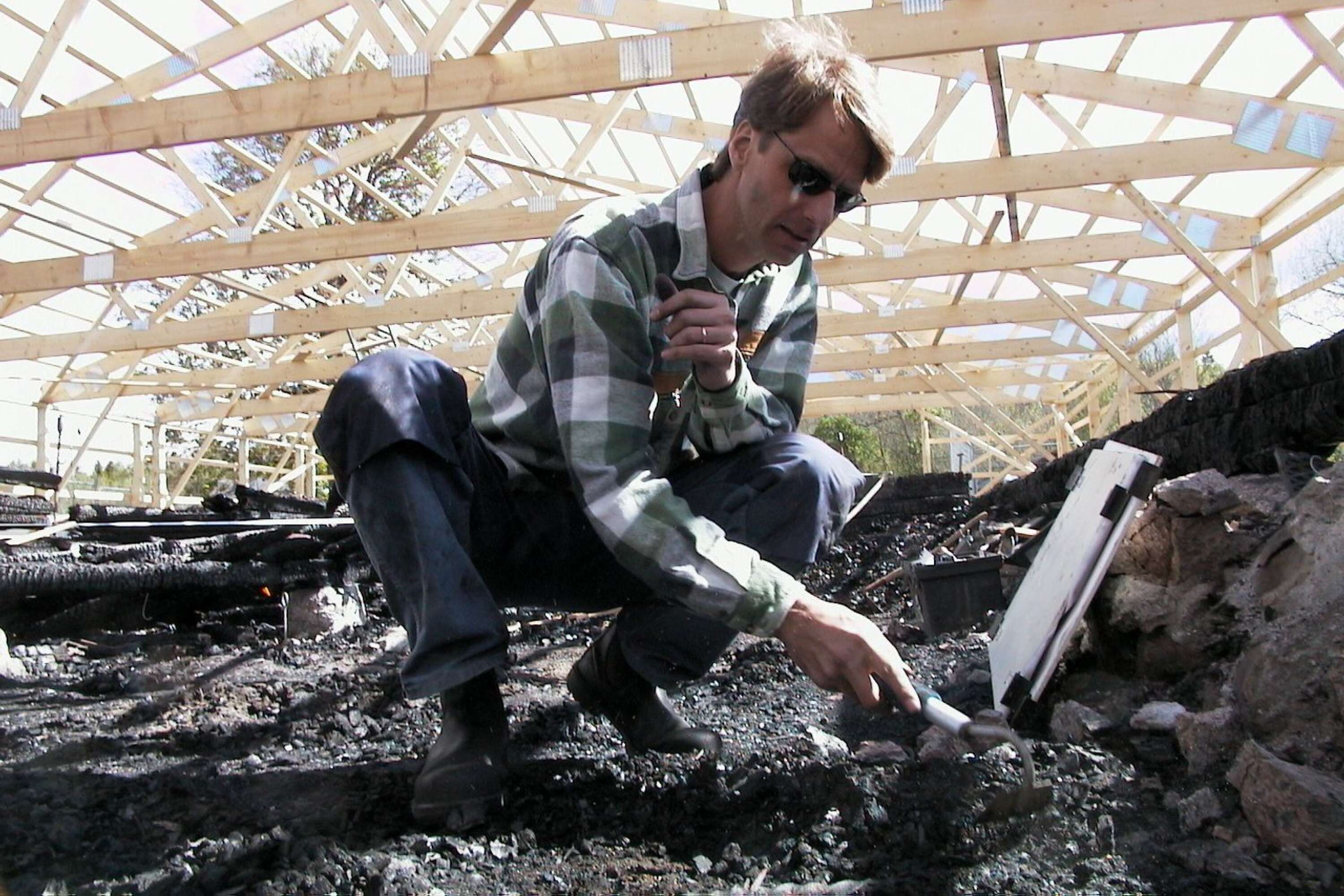 Arkeolog Rikard Hedvall undersöker marken under den nedbrunna kyrkan.