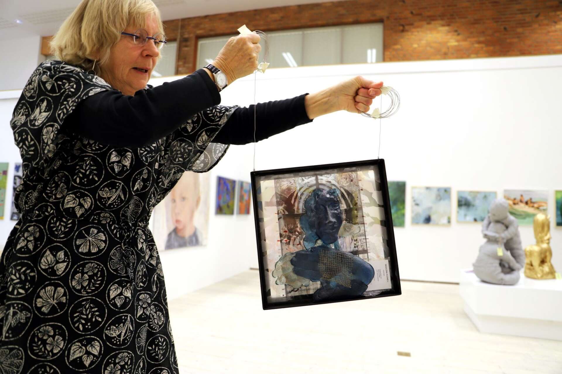 Elsa Hallbäck med starka armar visar ett glasverk av Ingalena Klenell.