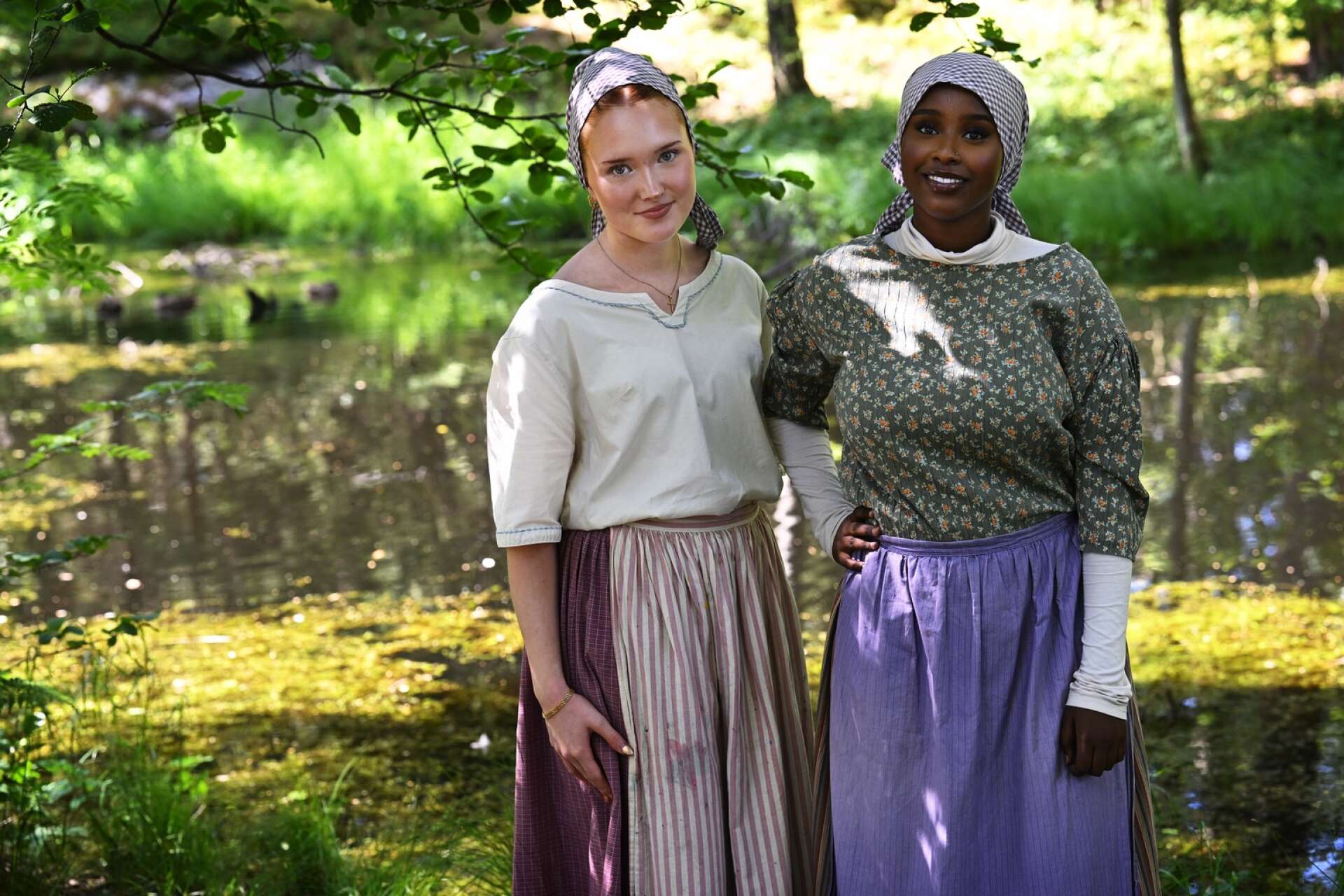 Ikran Said Abdullahi och Tilda Bergman Sandqvist iklär sig rollerna som pigor på sitt sommarjobb i Marieberggskogen.