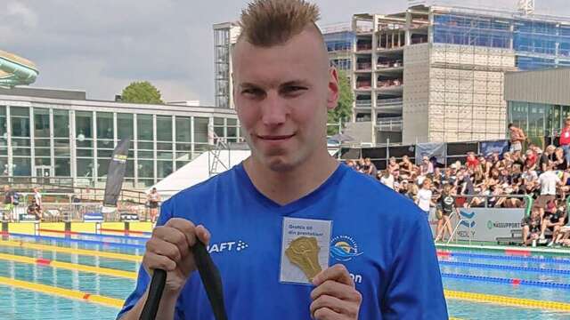 Tobias Klasson visar upp ett mästerskapstecken/guld och medföljande pris.
