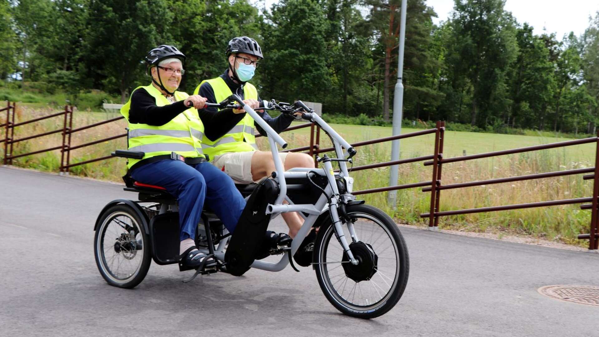 Iris Kjellberg känner sig helt trygg med att cykla och hon hjälper gärna till att trampa. Här cyklar hon tillsammans med personal Edvin Mellgren.