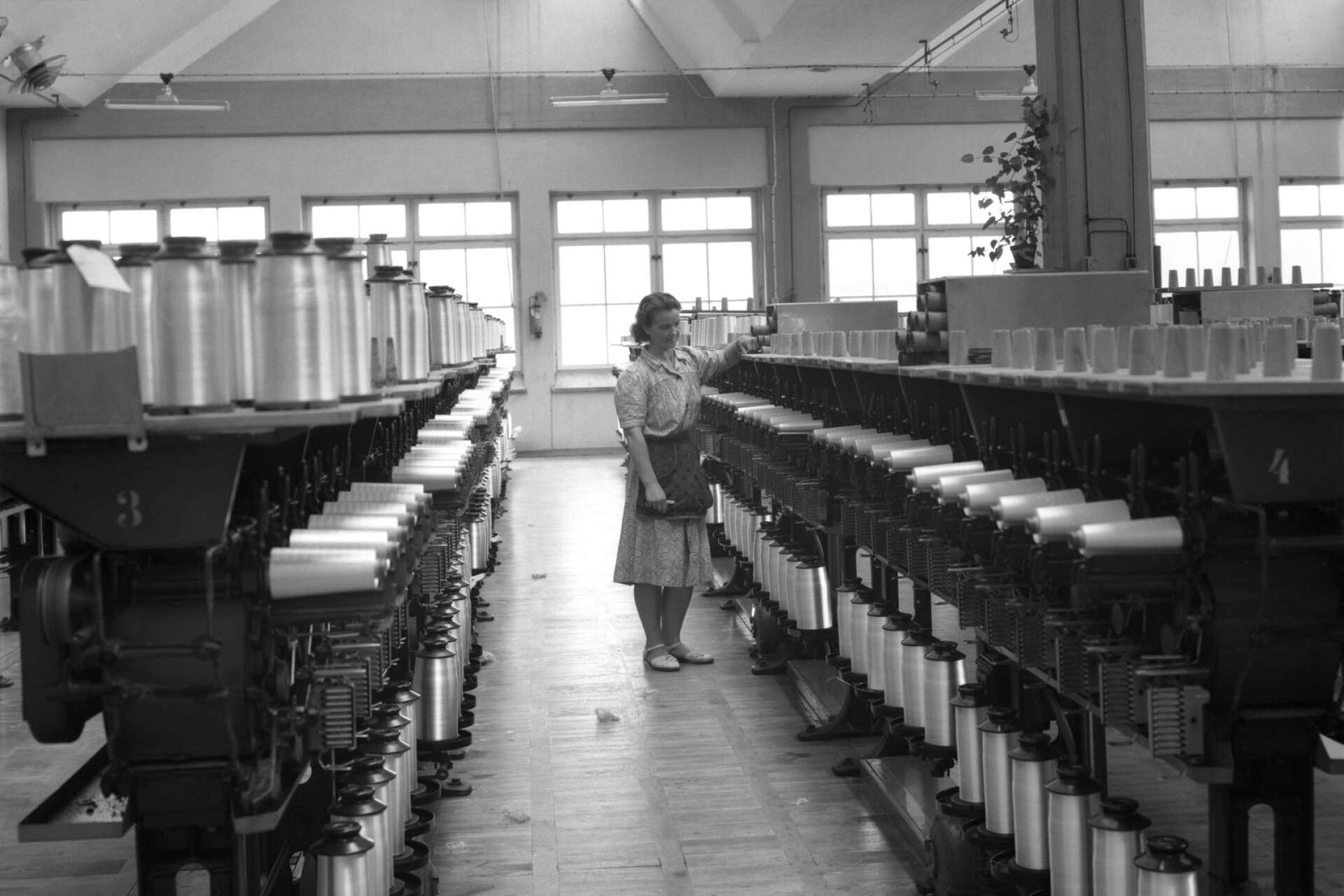 En arbetare framför trådrullarna hos Svenska rayon i Älvenäs. Fabriken invigdes 1943 och var en av de största arbetsgivarna inom textilindustrin i länet.