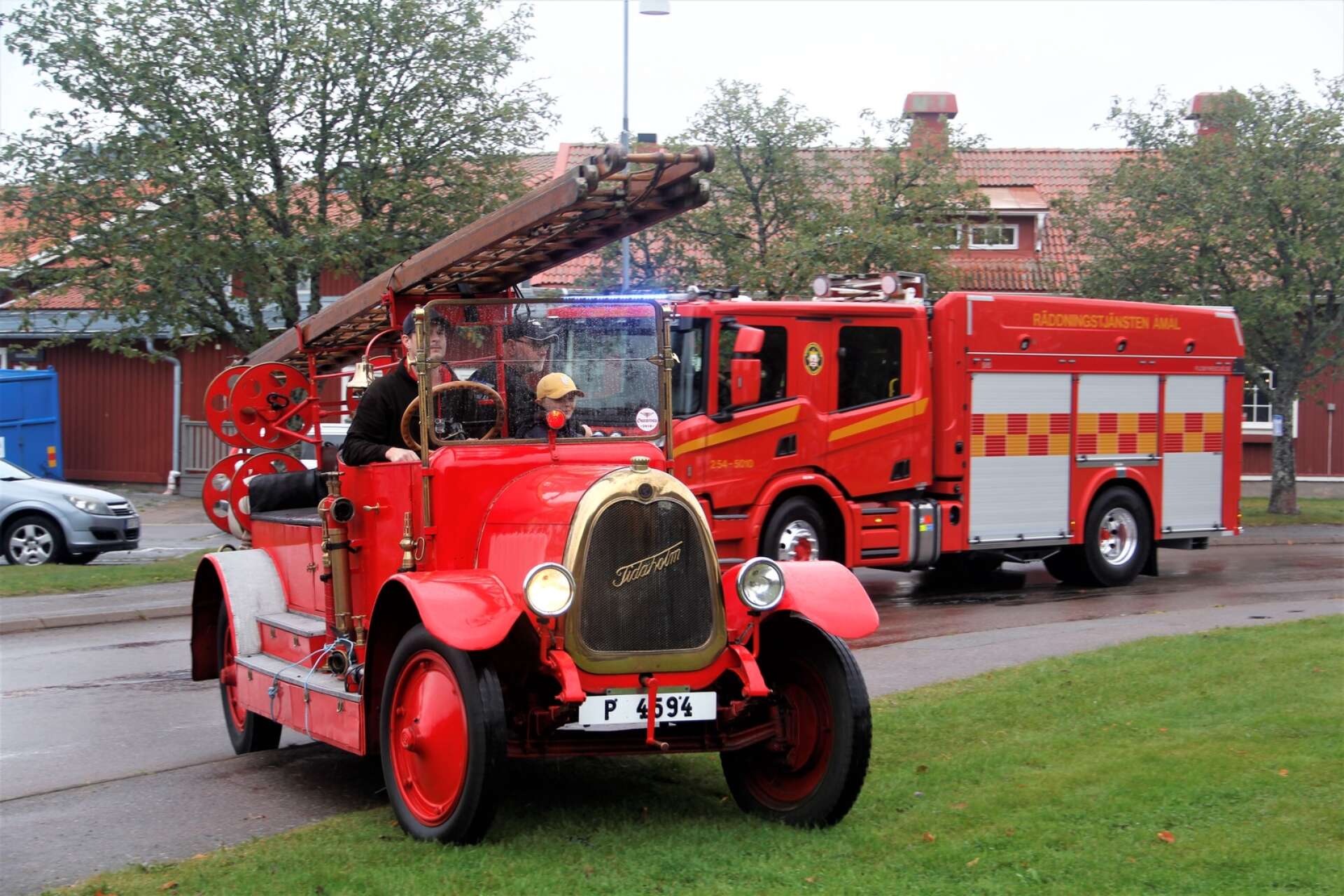 Den nya brandbilen 254-5010 rullade in på gräsmattan vid Gamla kyrkan med sirener på, anförd av den veteranbrandbil som kallas &quot;Tidaholmaren&quot;