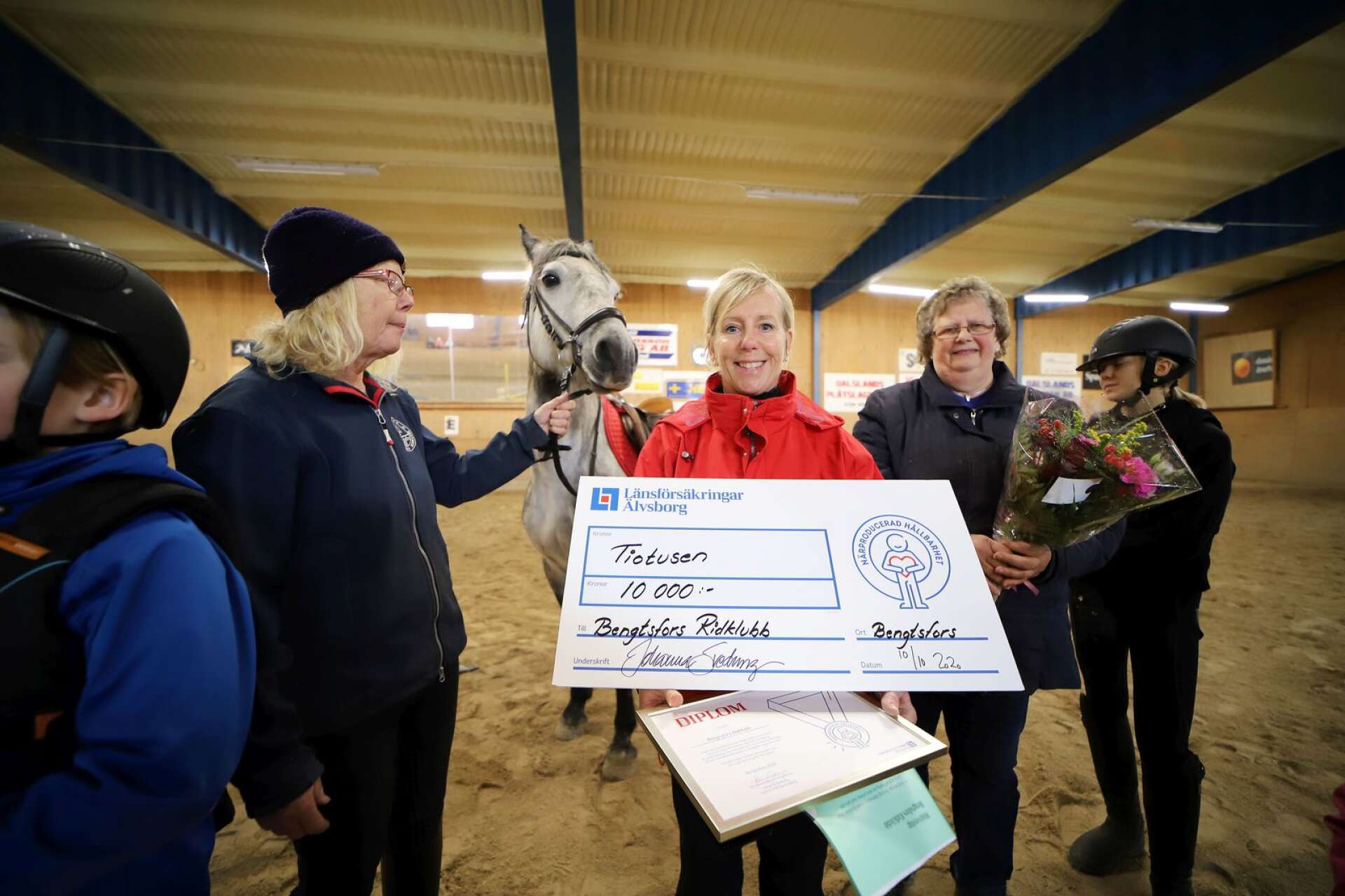 Lena Arwedahl från Länsförsäkringar Älvsborg delade ut priset Lovande förebilder till Bengtsfors ridklubb. Här med Mia Saga, ordförande, Margareta Johansson, stallchef, nyinköpta hästen Silver och en grupp ungdomar.