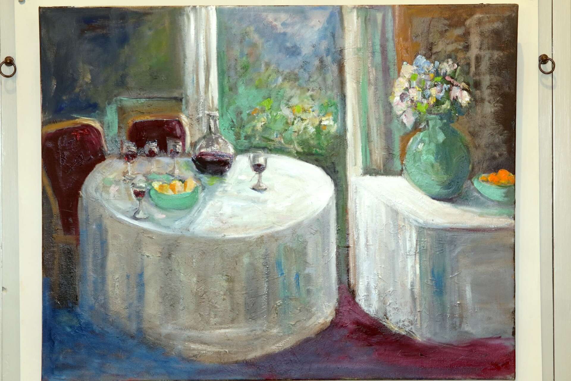 Ett verk med en känsla från förr, men ett dukat bord, glas, frukt och blommor.
