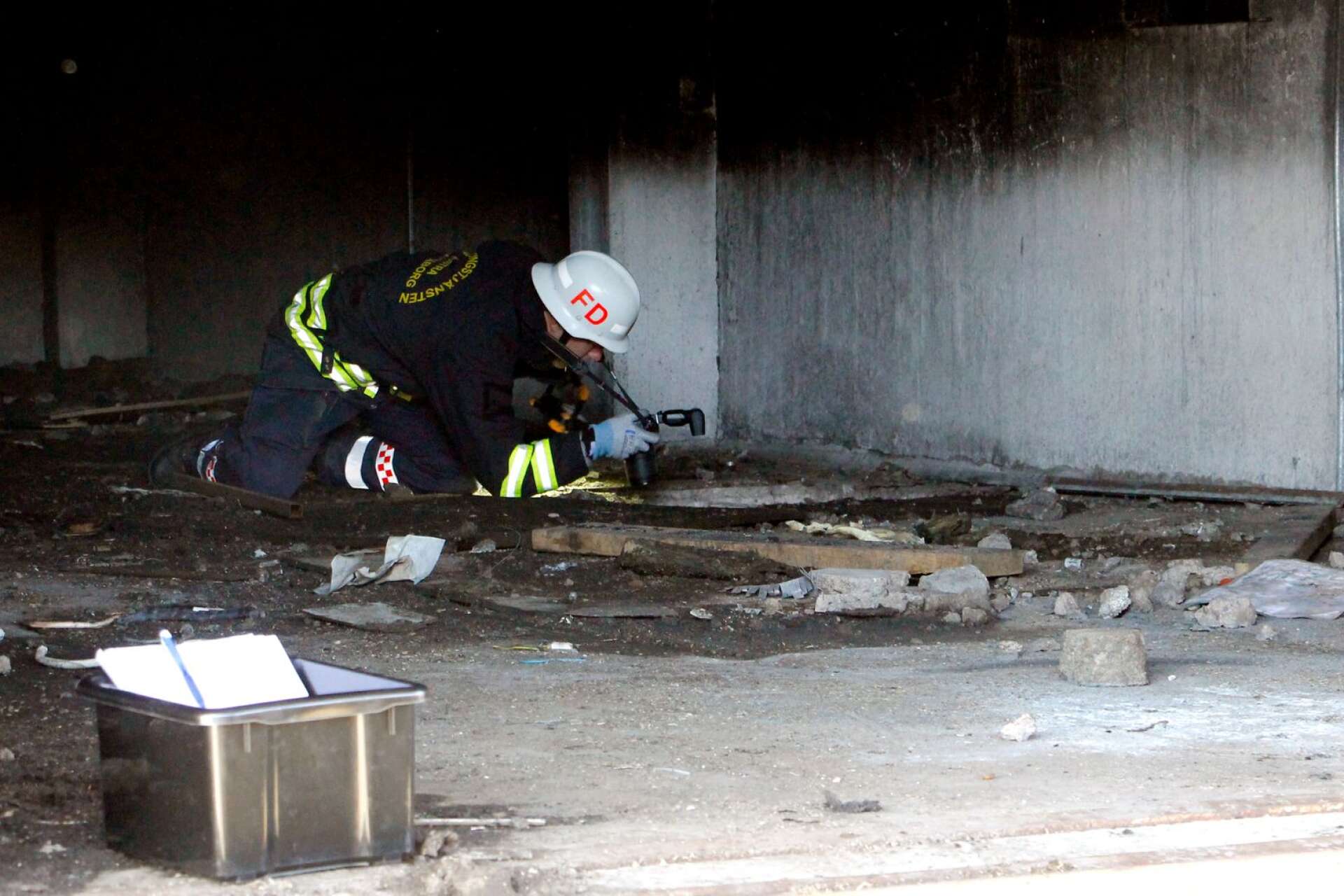 Brandingenjör undersöker hålen i betonggolvet där rökdykare skadades.