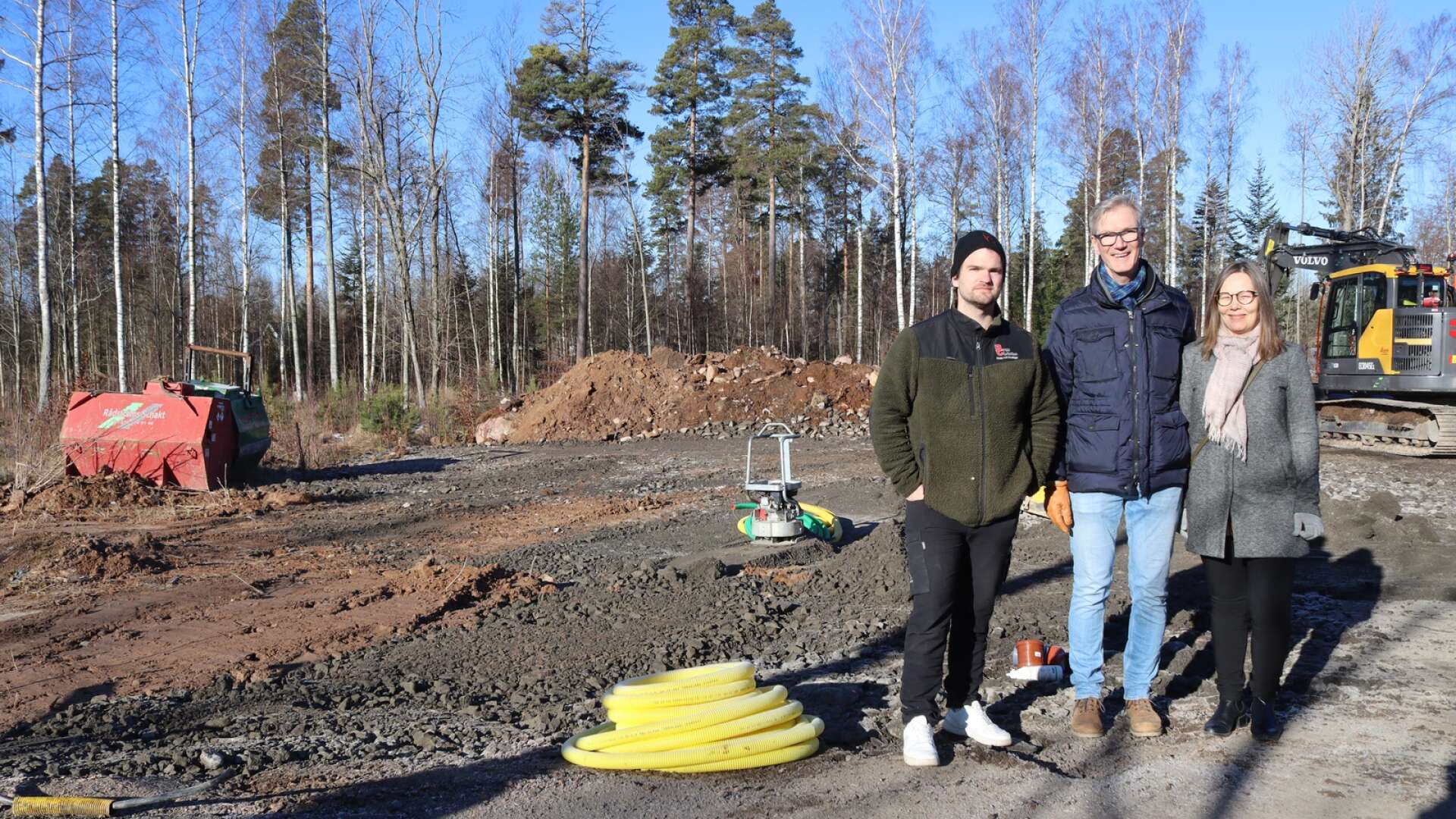 Platschef Martin Andersson visar Arvid och Linn Lundtoft hur långt markarbetet har kommit vid deras hus.