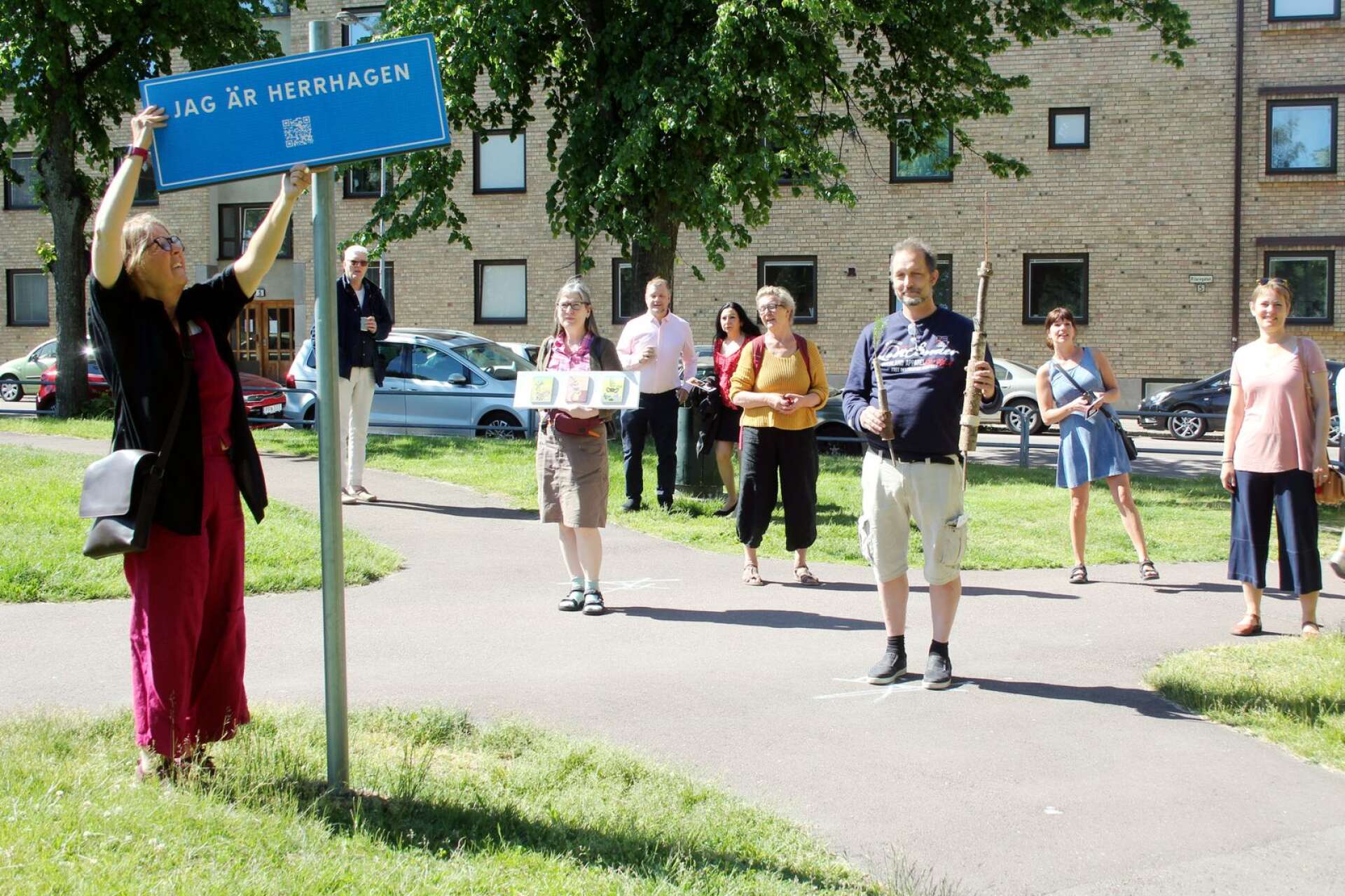 Margaretha Jansson sätter upp skylten som ger besökarna koden till hennes bildspel med människor på Herrhagen. Det är en av punkterna på vandringen där totalt 14 konstnärer ställer ut sina verk.