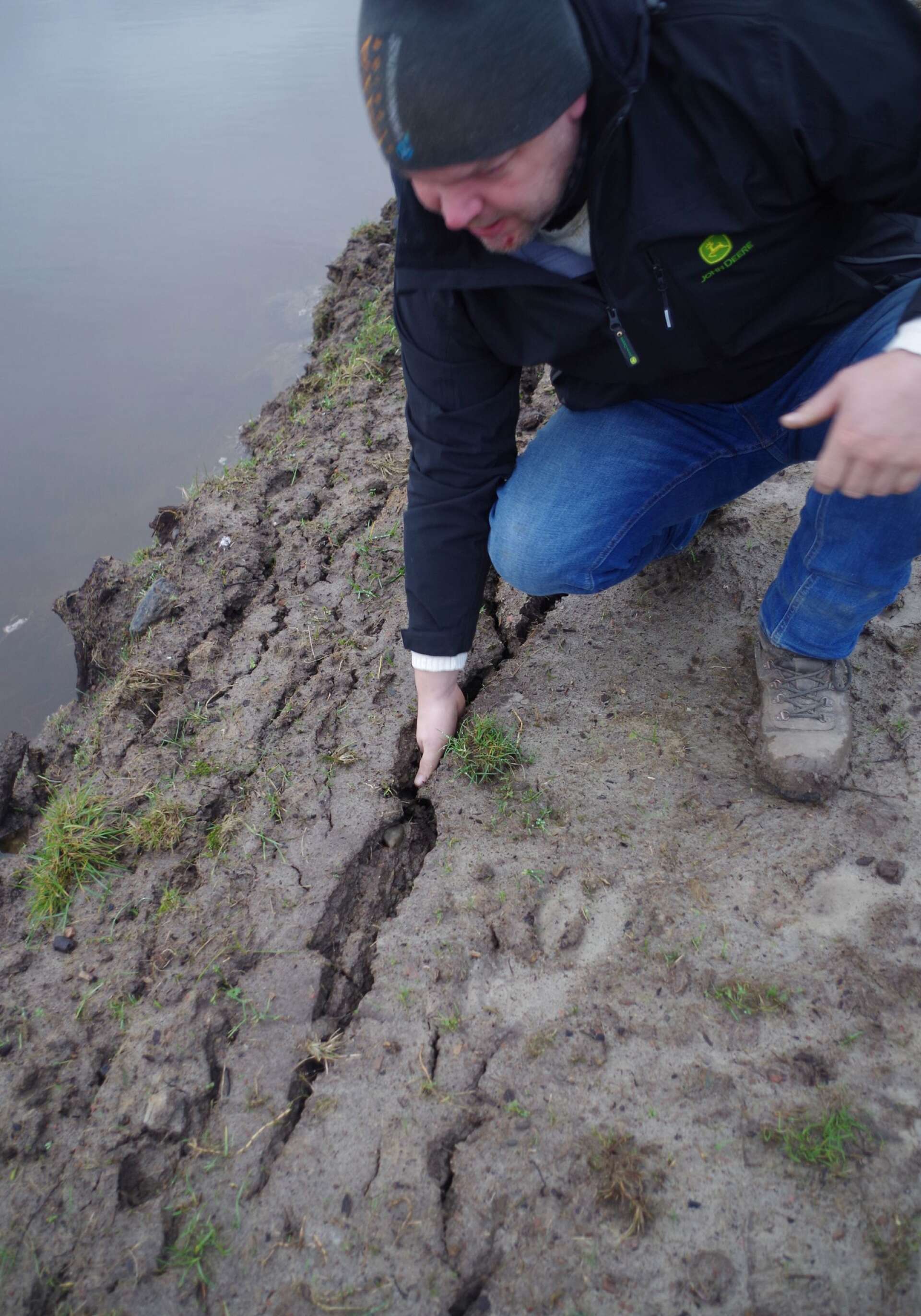 Ola Axelsson pekar på djupa sprickor som öppnar sig i leran på vallarna efter regn uppifrån och tryck från både sidan och underifrån.