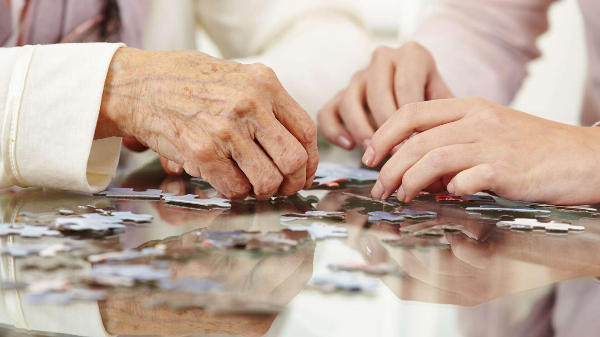 Old hands solving jigsaw puzzle in a nursing home