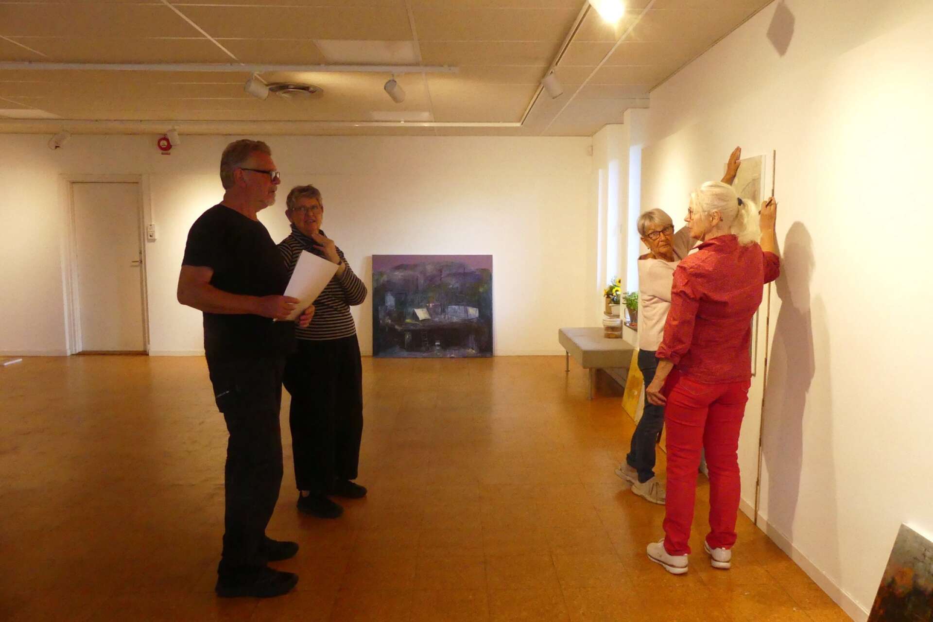 Diana Wennberg, Britt Svarfvar och Maritha Sundberg från Konstbild -82 Åmåls konstförening, som är arrangör, hjälper Stefan Ceder att hänga utställningen.