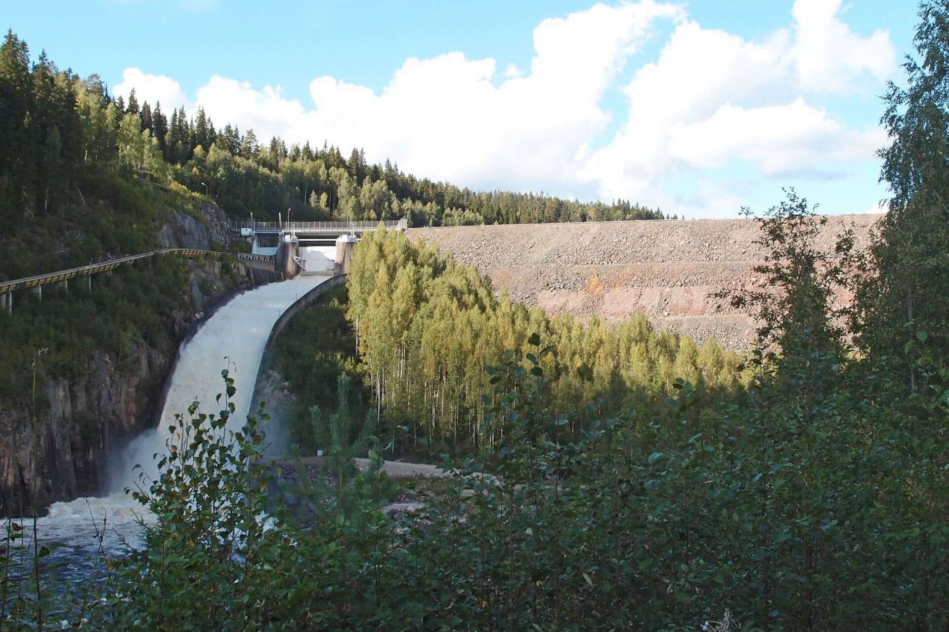 Den 80 meter höga Höljesdammen som den såg ut före restaureringen 2014, då utskovet ökades ut på flottningsrännans bekostnad.   