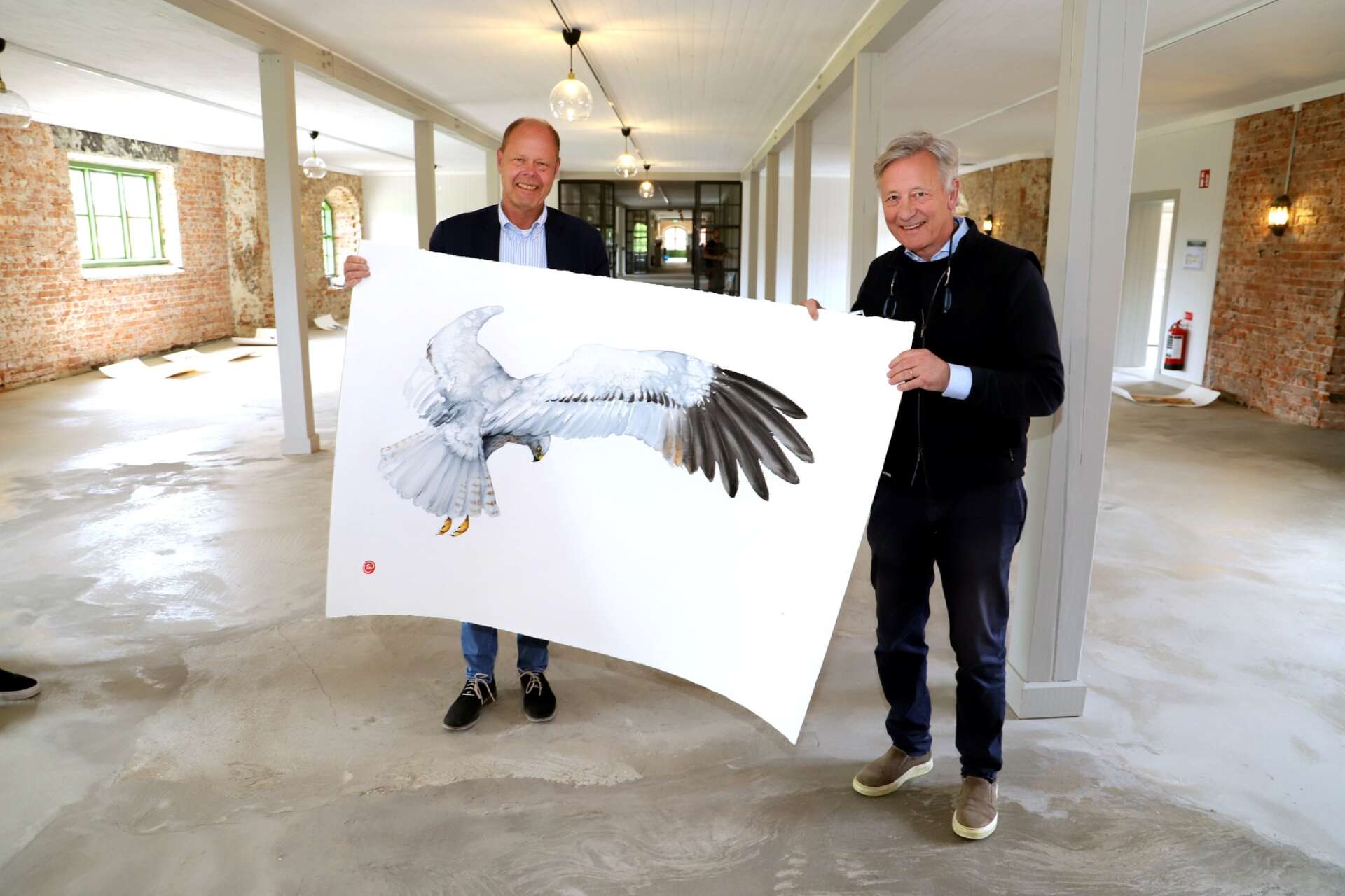 Mats Bergman och Hans Karlander visar upp en av Karl Mårtens bilder. Han är en av de första konstnärerna att ställa ut i den sprillans färska konsthallen i Borgvik.